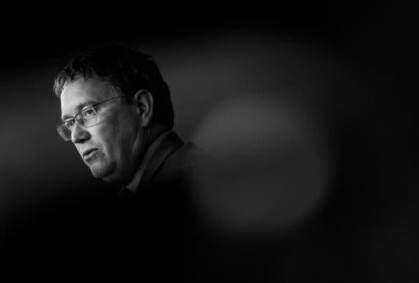Representative Thomas Massie looking to one side, his head and shoulders isolated on a dark background.