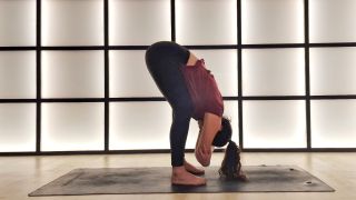 Woman doing a forward fold with hands on elbows