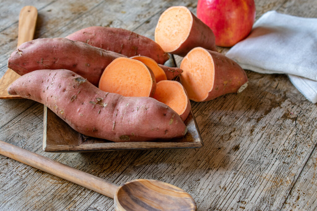 uncooked sweet potatoes on a rustic plate served on a wooden table