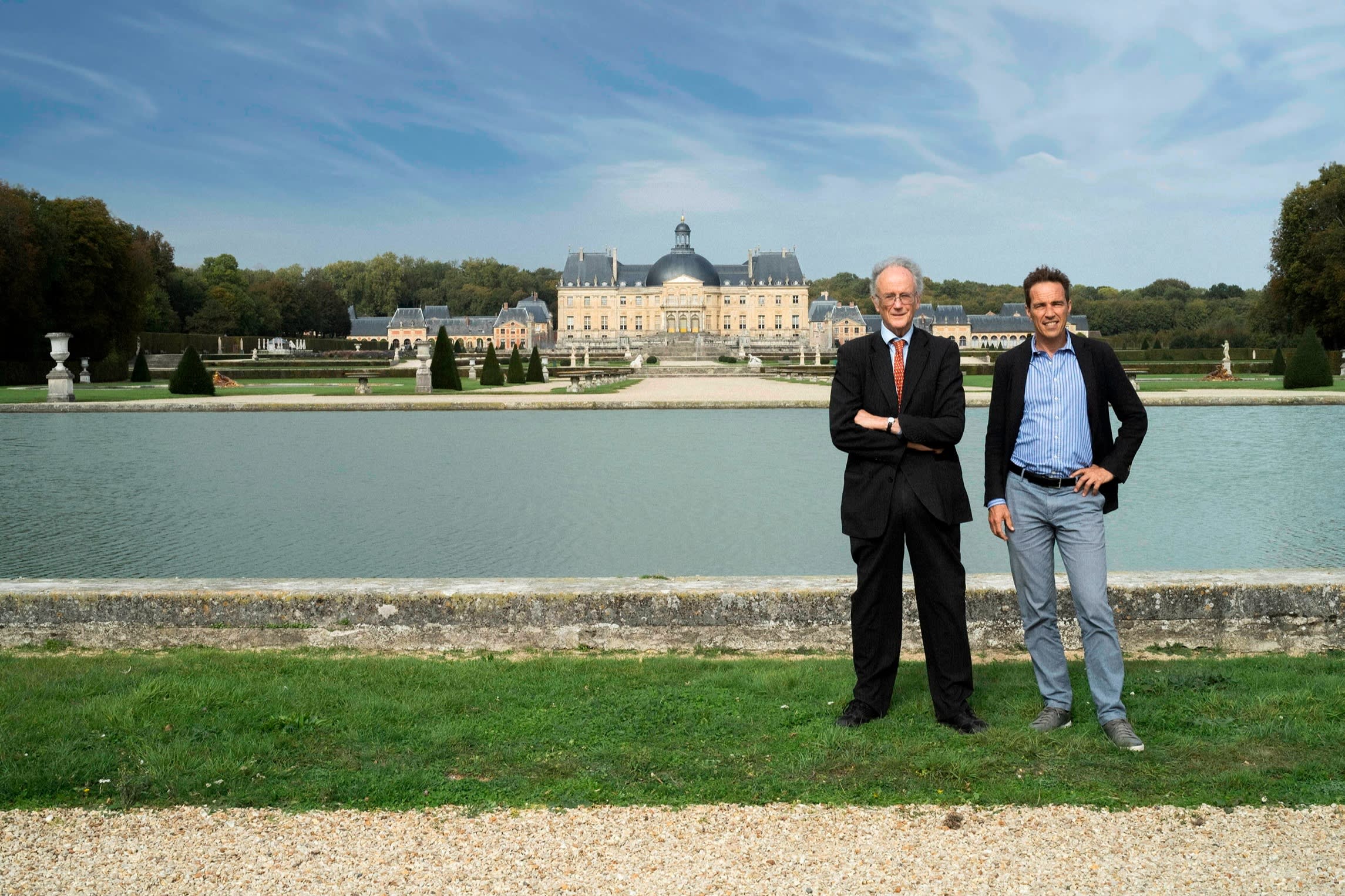 Two men pose in front of the chateau Vaux-le-Vicomte