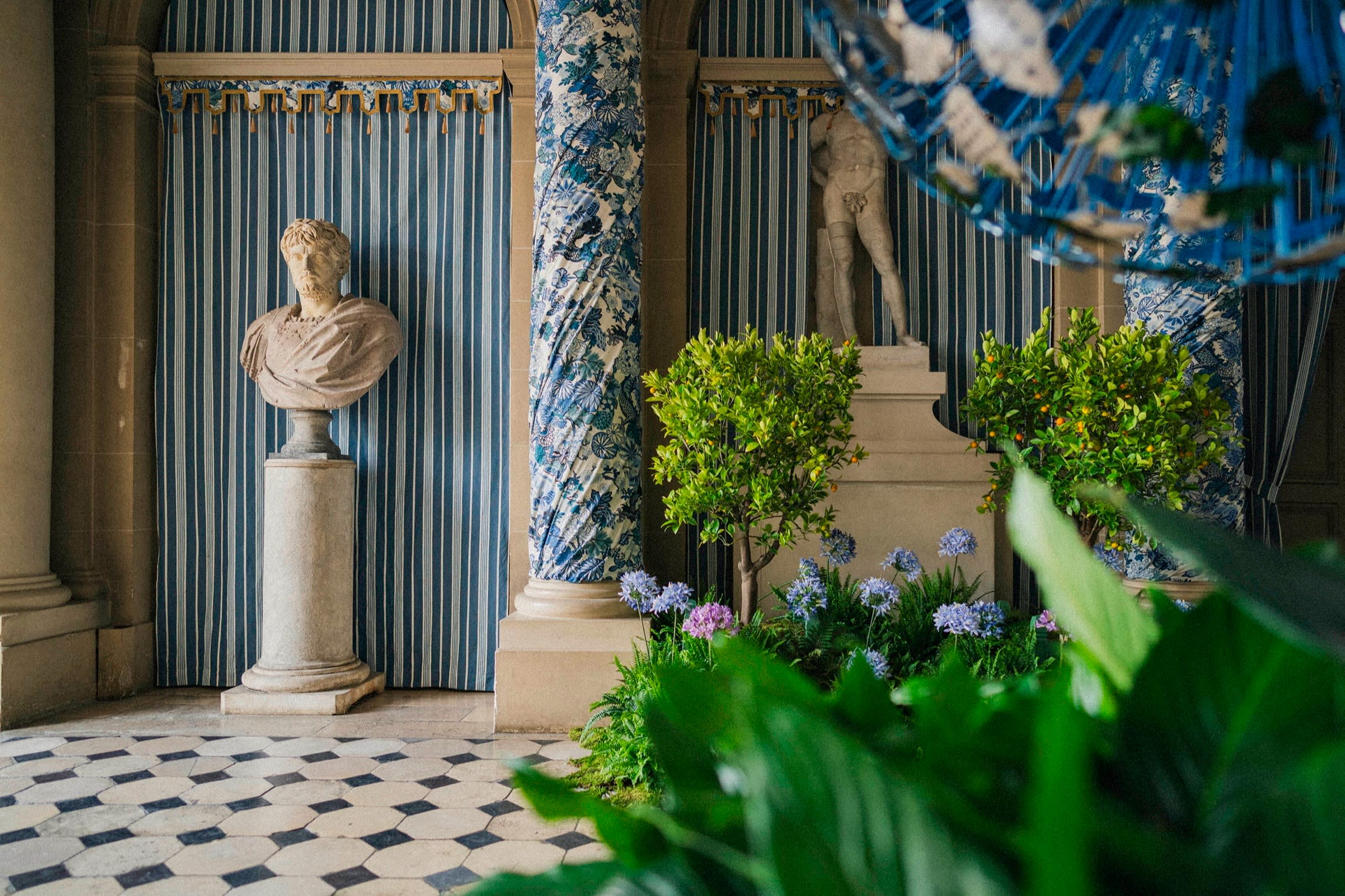 Blue and white fabric wrapped around pillars and agapanthus and orange trees in the chateau vestibule