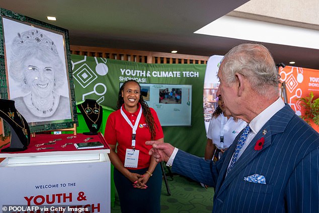 King Charles speaks to an entrepreneur during a visit to a Tech and Innovation showcase at Nairobi Garage after spotting a portrait of his wife