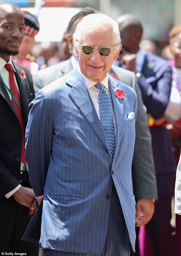 King Charles III smiles as he arrives with Queen Camilla for their separate engagements inside Eastlands Library