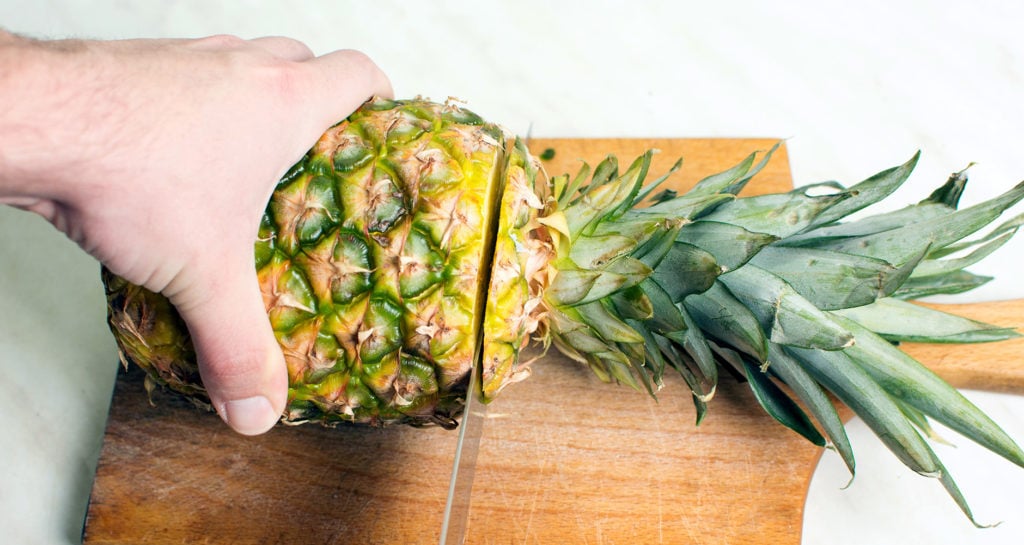 cutting the top off a pineapple
